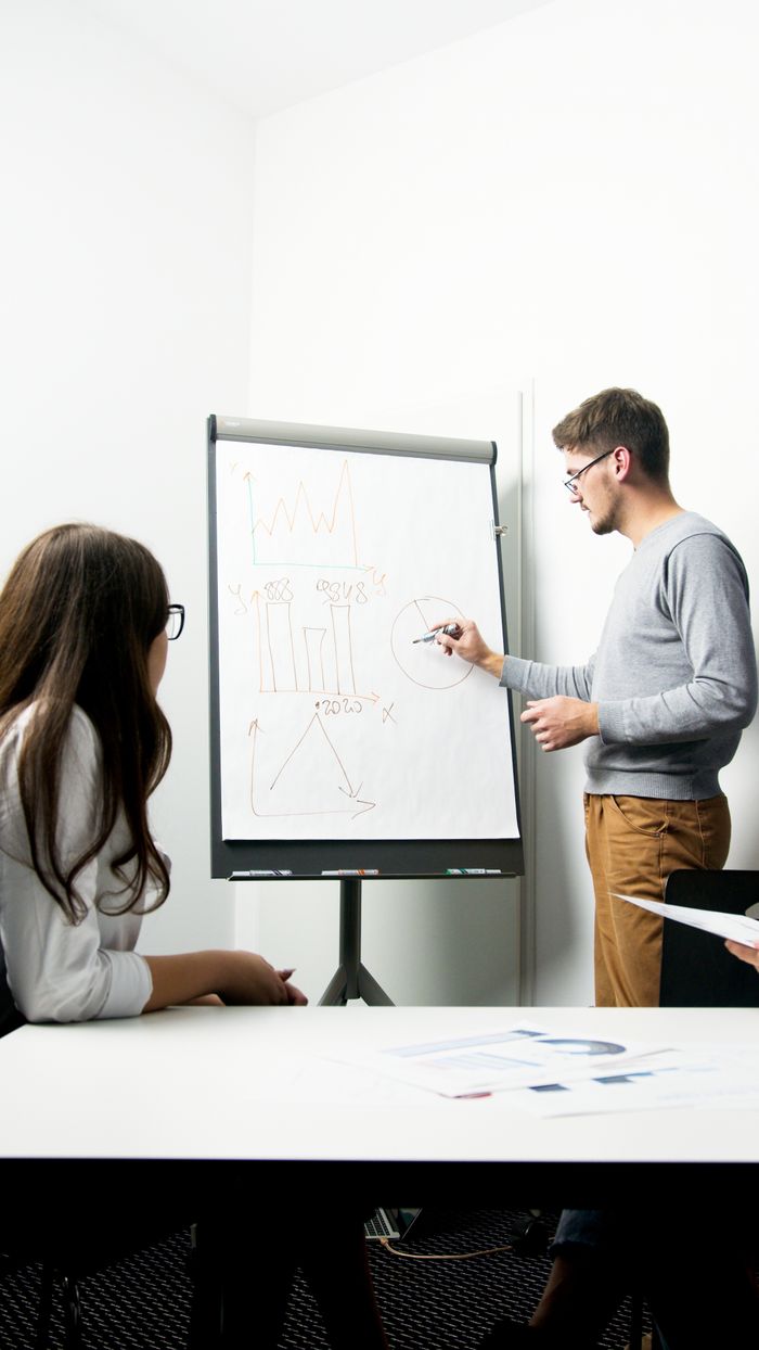 services-04 A businessperson giving a presentation with charts in a modern office environment.