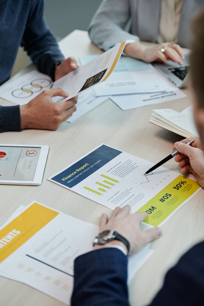 team-02 Professionals working together in an office, analyzing financial reports and documents with focus on graphs and teamwork.