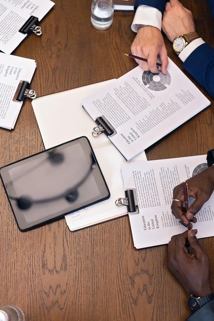 team-04 Top view of a business meeting with hands, tablets, and documents on a table.